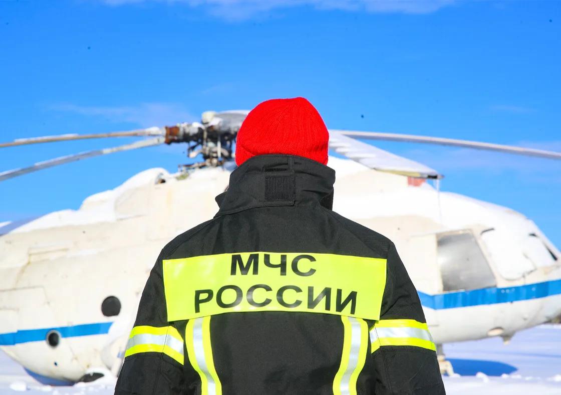Человек в форме МЧС России у вертолёта Ми-8 на заснеженном аэродроме